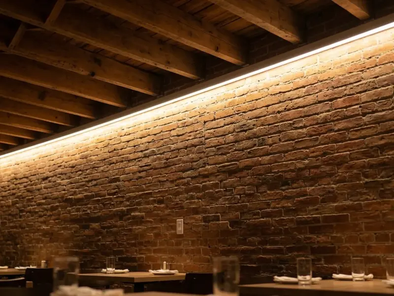 Warm 120V LED strip cove added along a brick wall and timber ceiling