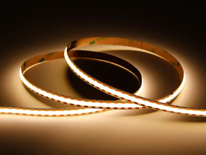 Powered UT-C528-8-FC free-cut COB LED strip coiled and lit, with cut-point markers along the run showing it can be trimmed anywhere