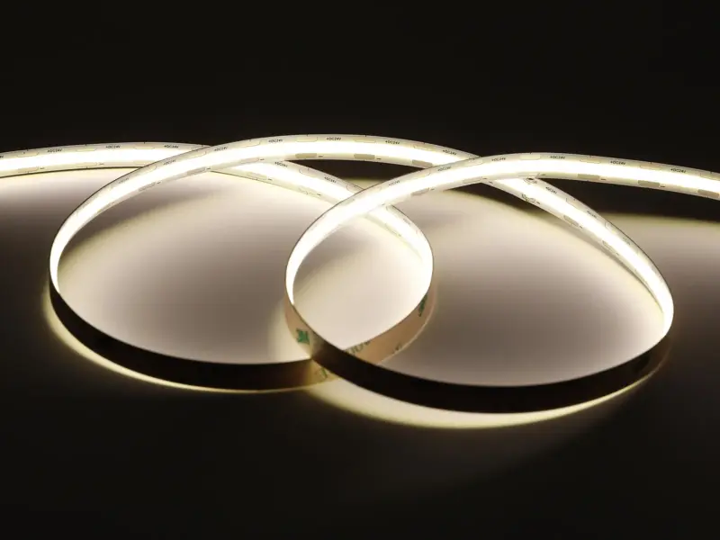 Standard COB LED strip coiled and glowing with even warm white light