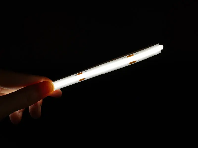Hand holding a lit Dome Diffused CSP strip, the domed silicone extrusion spreading light into an even line