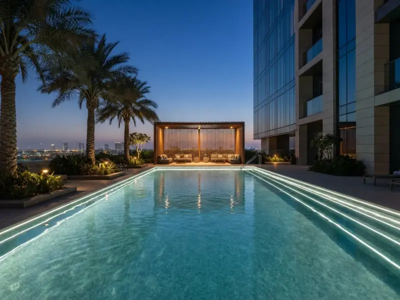 Hotel rooftop pool at dusk with cool-white strip light outlining the submerged pool walls and step edges