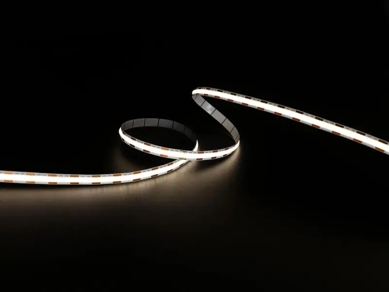 Mini Cut CSP strip lit in warm white, curved on a dark surface with closely spaced cut points along the board