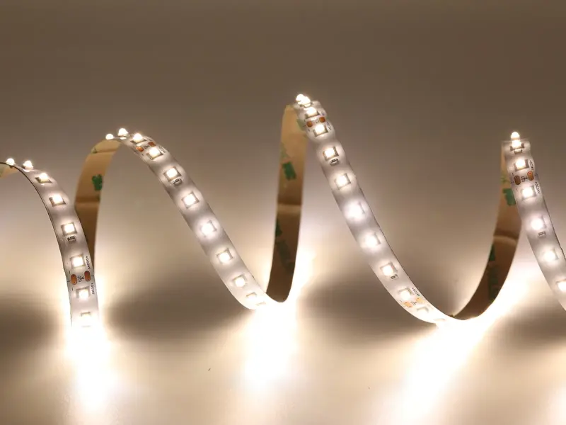 Constant-current 2835 LED strip coiled and lit in warm white, 3M adhesive tape along the back
