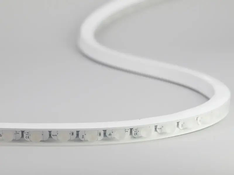 White silicone-jacketed LED strip with round optical lenses, marked DC 24V, lit in cool white