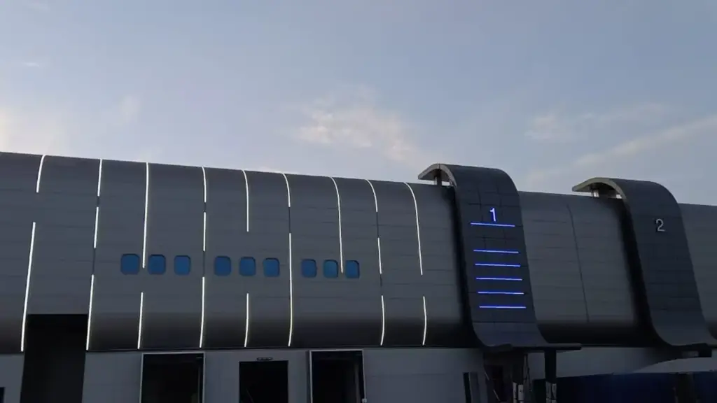 LED neon flex lit at dusk on the curved facade of JAFZA South Logistics Park, with white lines and blue level markers on the stair tower