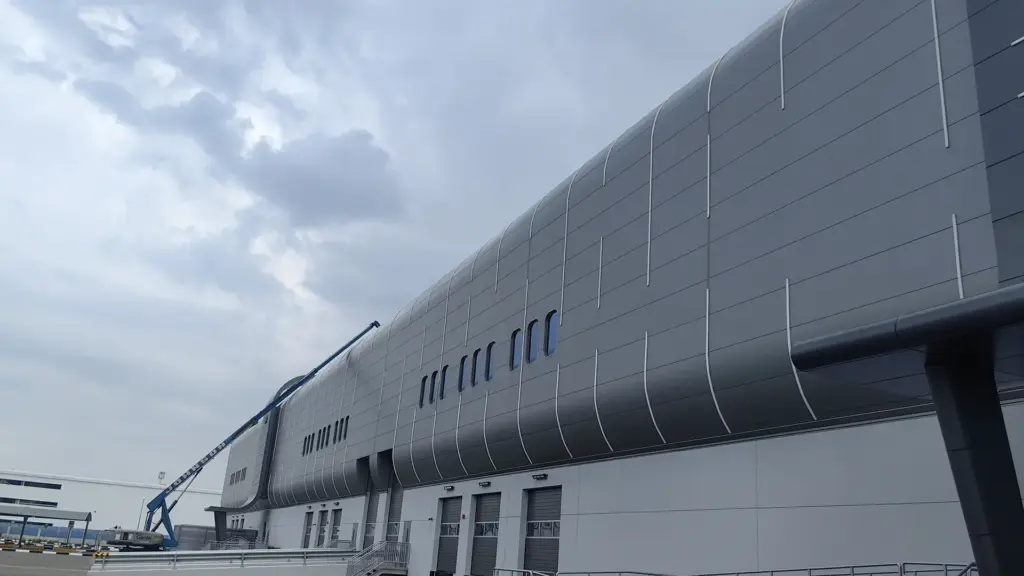 Curved metal facade at JAFZA South Logistics Park in daylight, with installed silicone LED neon flex lines following the panels