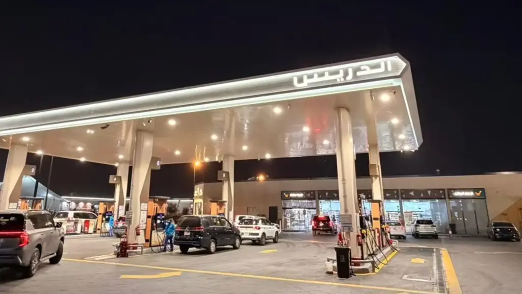 Aldrees petrol station canopy at night with a 6500K white LED neon flex line along the fascia edge, the Aldrees sign in Arabic and cars at the pumps