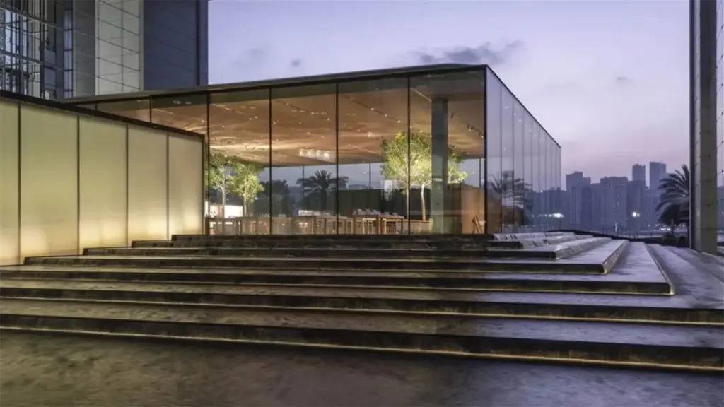 Glass-fronted Apple Store at Al Maryah Island, Abu Dhabi, at dusk, with wide stone steps in front of the entrance