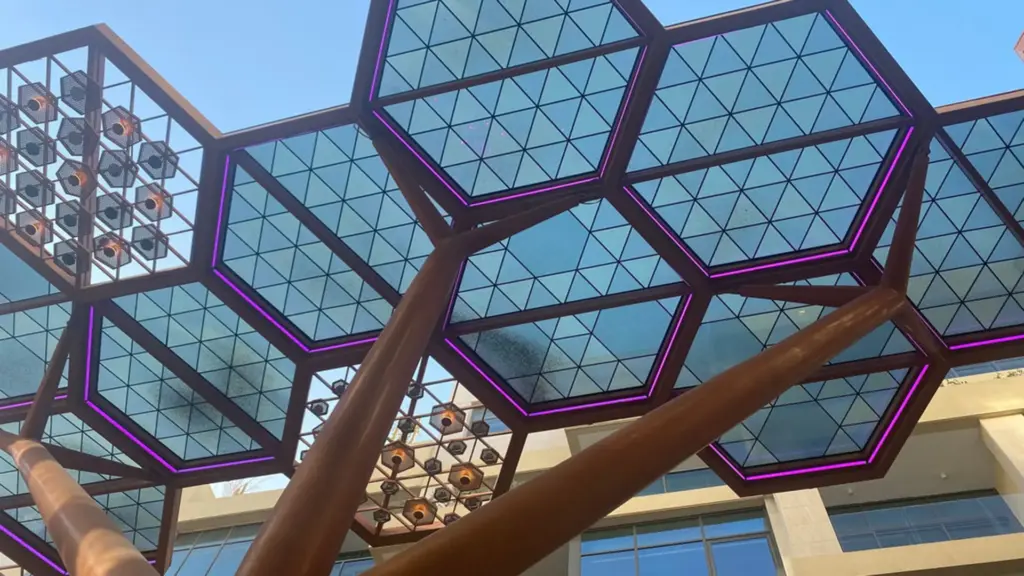 Hexagon glass canopy panels at the Crystal Corridor in Doha seen from below, each outlined in magenta LED neon flex