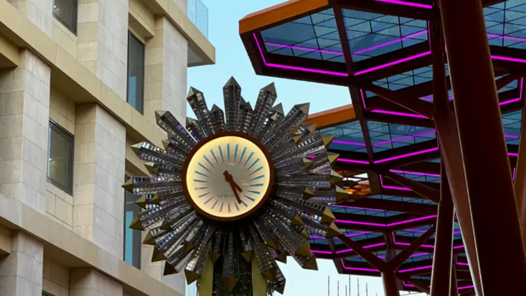 Crystal Corridor clock sculpture in Doha beside the steel canopy, with magenta LED neon flex along the hexagon frames