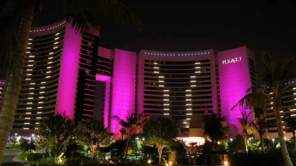 Grand Hyatt Dubai curved towers at night, washed in magenta light, with rows of lit windows and a HYATT sign