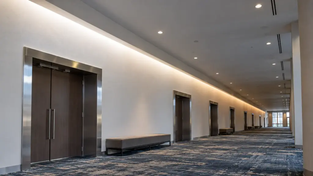 Long SMD LED strip cove in a convention center concourse, the far end visibly dimmer and warmer